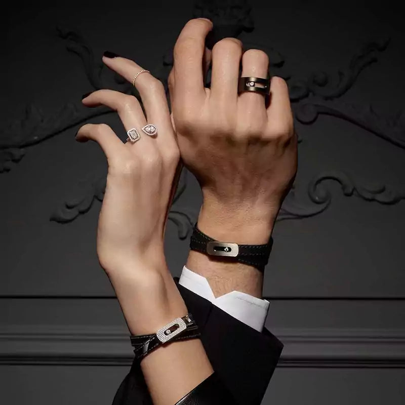 Close-up of hands wearing rings and a bracelet against a dark background