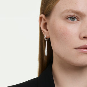 close up of a woman wearing silver and crystal hoop drop earrings on a white background