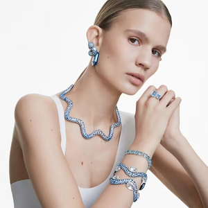 Model wearing Millenia jewelry set — wavy blue gemstone necklace, matching earrings, bracelets, and open ring