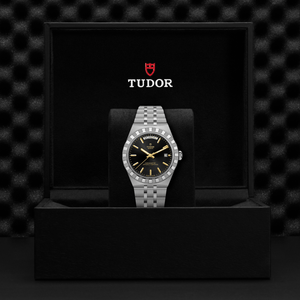 Tudor watch in a black box with the Tudor logo on a dark textured background