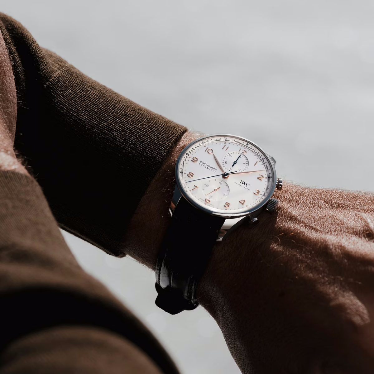 Close-up of Portugieser Chronograph on wrist showing silver dial, chronograph subdials, steel case and black alligator strap