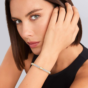 Close-up of wrist wearing Triple Diamond Caviar Bracelet 6mm showcasing three diamond stations and 18K gold accents on gray