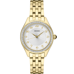 Gold tone Seiko watch with a white dial and crystals around the bezel on a white background