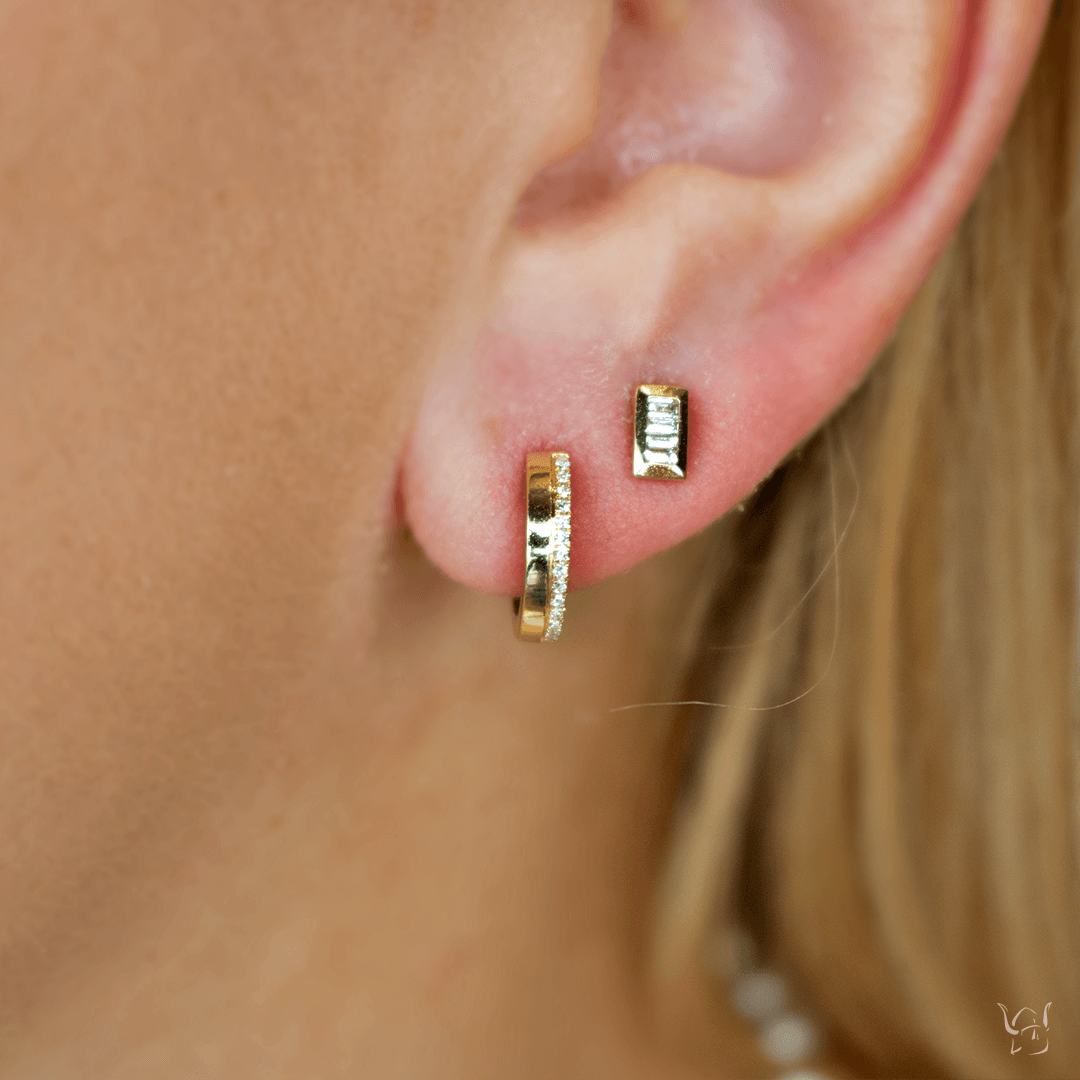 Close-up of 14k yellow gold 0.08ctw diamond huggie earring showcasing pave-set diamonds on blurred skin background