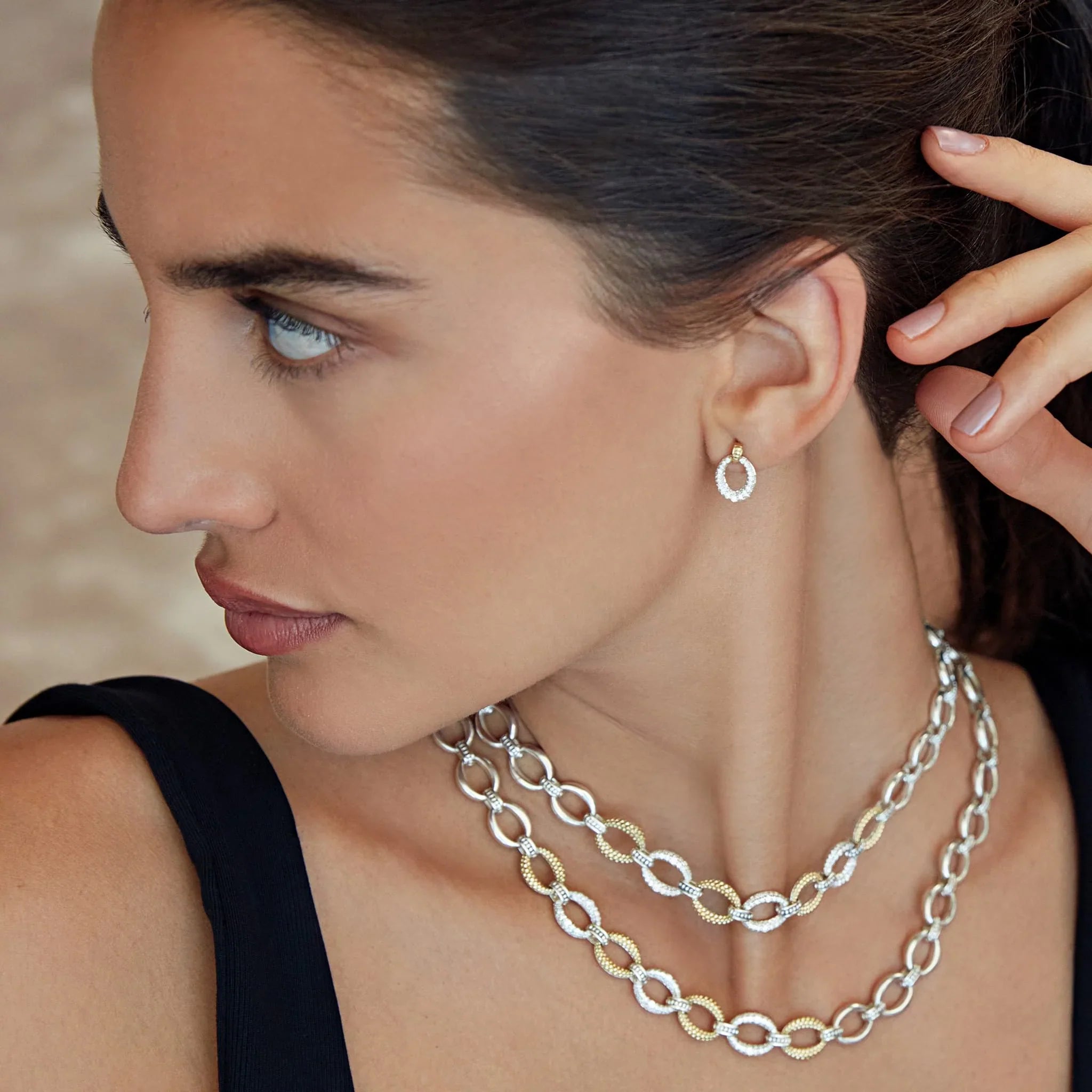 Three-quarter left view of oval drop diamond earring in 18k yellow gold with caviar beading worn on model’s ear against neutral background