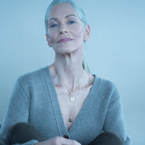 Front view of Slim Britt gold locket necklace on model showcasing slim side profile and layered pendants with gray background