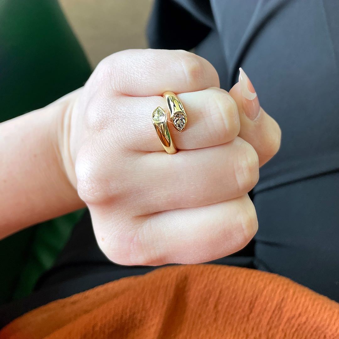 Close-up of Toi et Moi 18K yellow gold ring showcasing two pear-shaped diamonds totaling 0.67 ct on a finger against dark clothing
