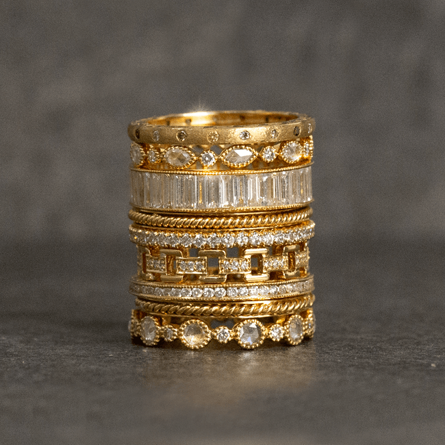 Stacked gold rings featuring baguette and round diamonds, milgrain edges and rope-like bands