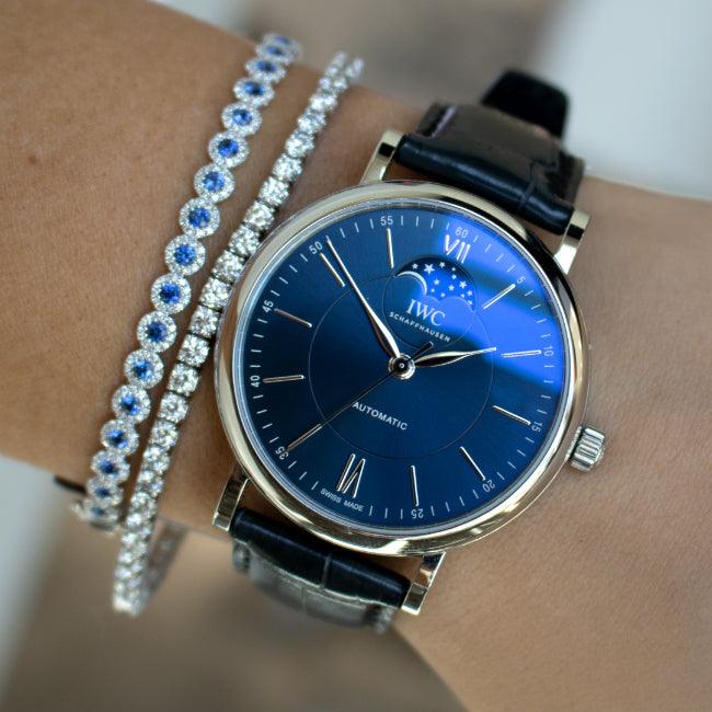 Wrist view of IWC automatic watch with blue sunburst dial, moonphase and black leather strap, paired with diamond bracelets