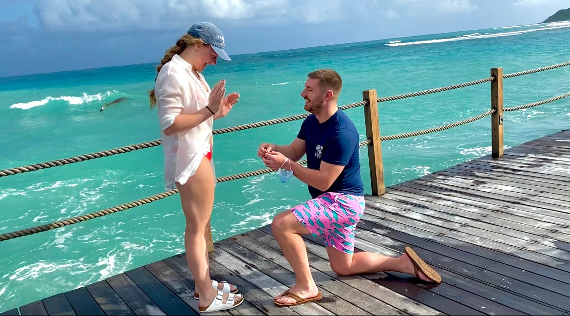 Madison and Mitchell: he kneels to propose on a wooden pier by turquoise ocean waves