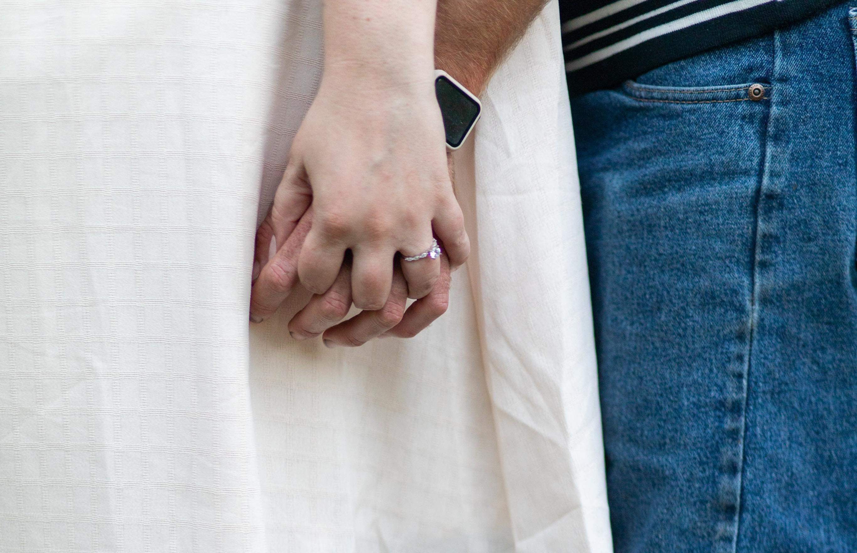 Katie and Tim holding hands, Katie's left hand showing an engagement ring.