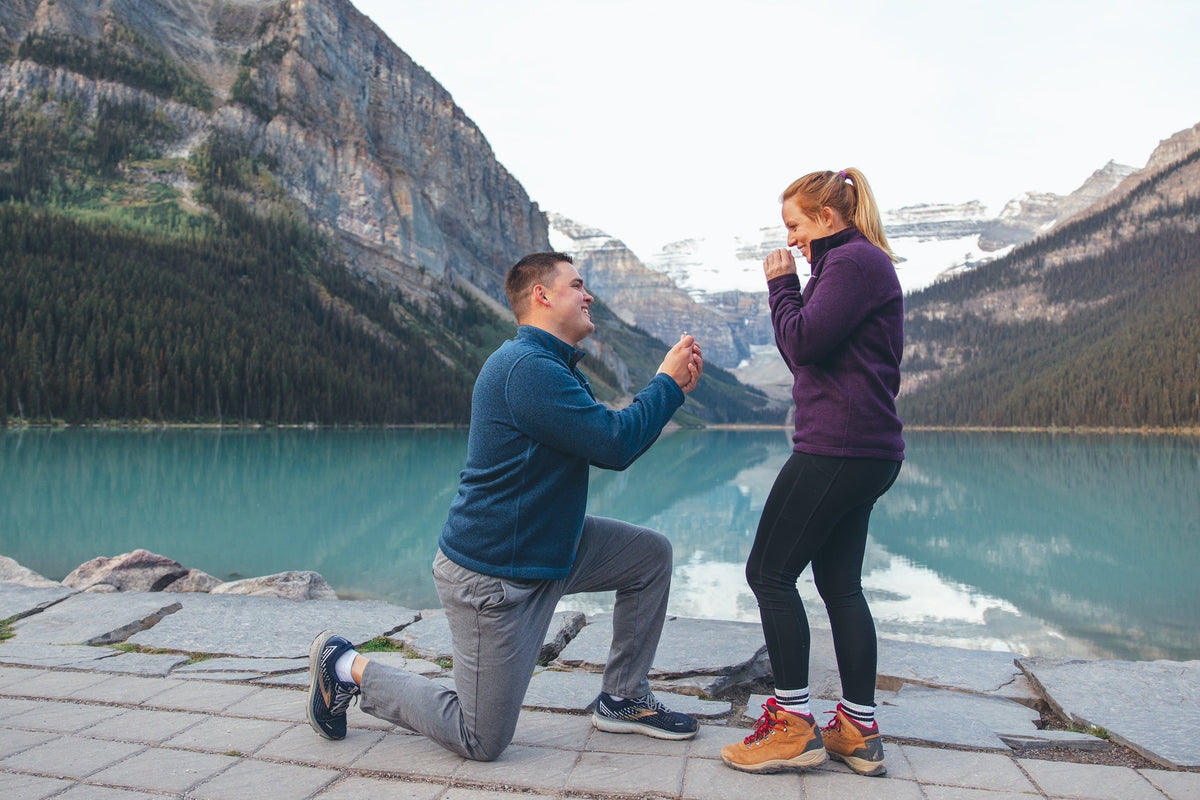 Man kneeling and proposing to a woman at Lake Louise in Banff National Park with turquoise lake and mountain peaks behind them