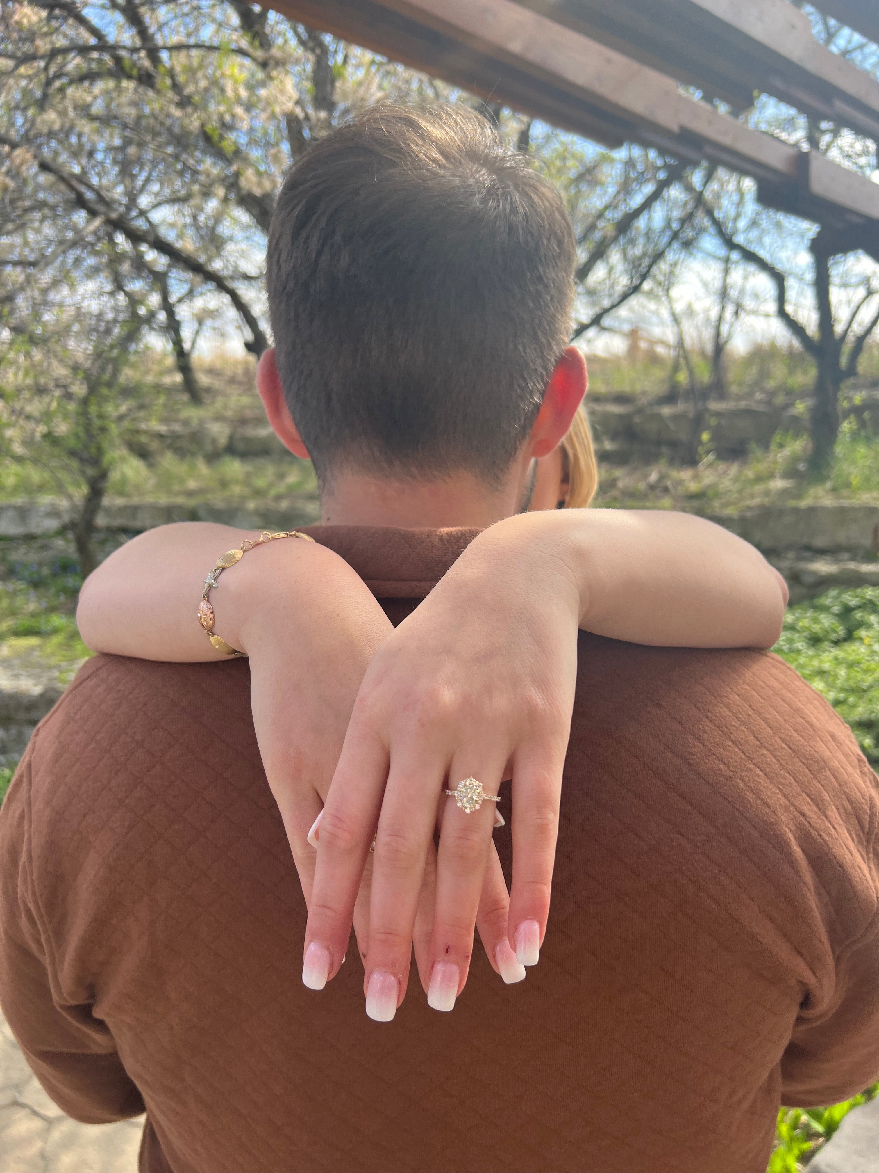 Grace and Jacob embracing; woman's hands over his shoulders showing an engagement ring on her left ring finger.
