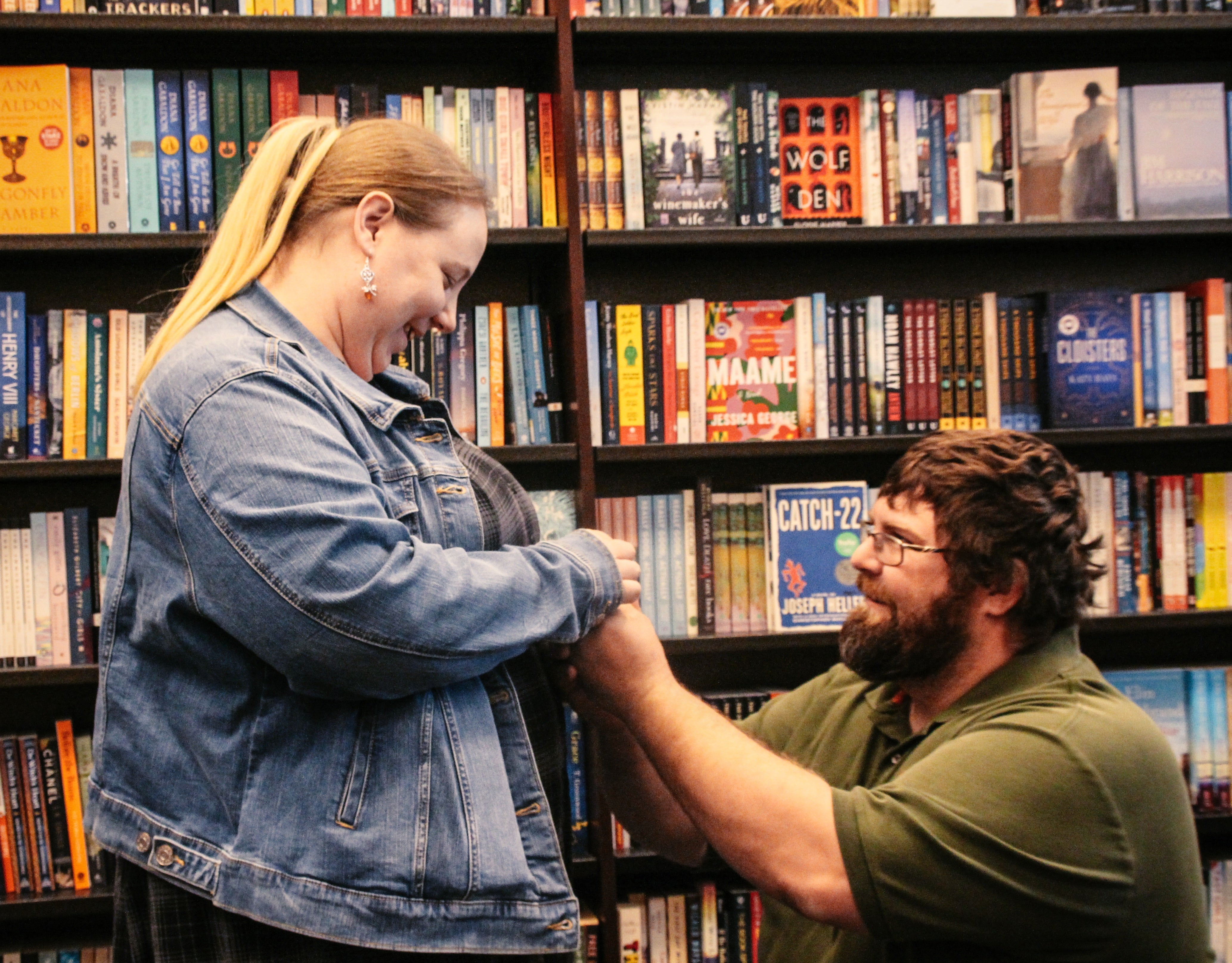 Woman smiling as a man kneels and proposes inside a Barnes & Noble bookstore