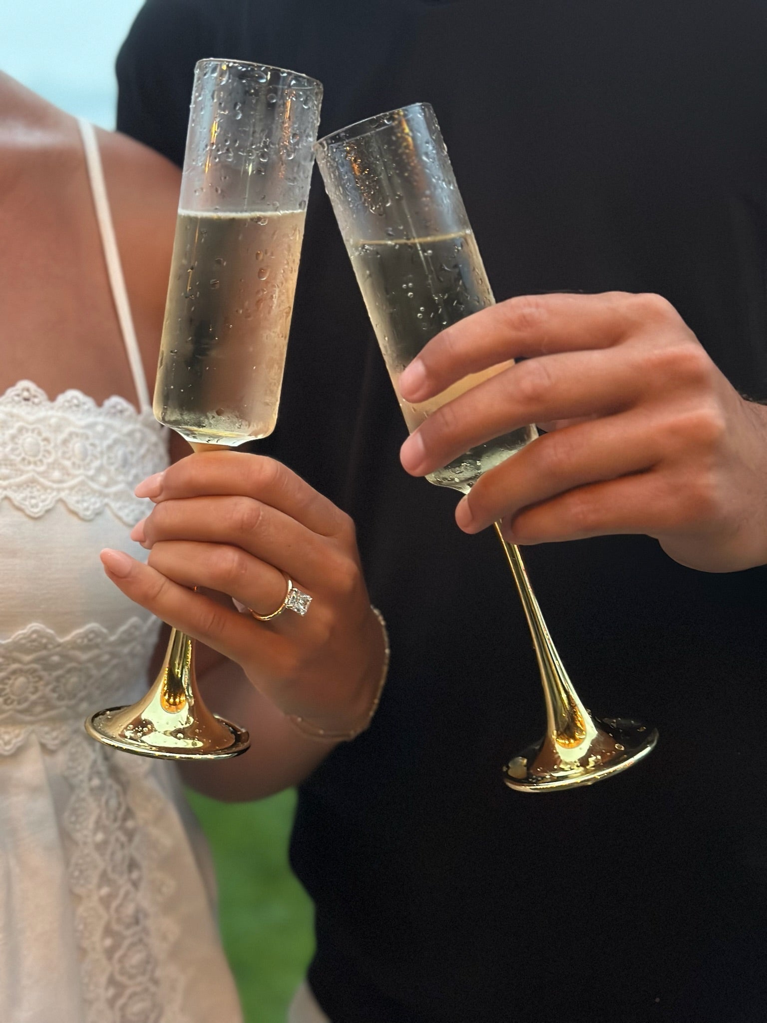 Couple clinking champagne flutes with woman wearing a radiant-cut yellow gold solitaire engagement ring