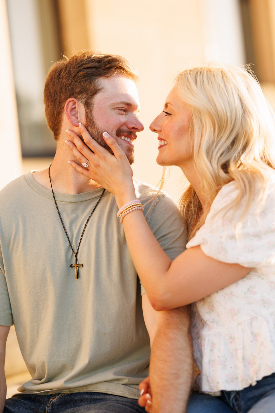 Megan gently touching Mitch's face, showing engagement ring as they smile during their proposal