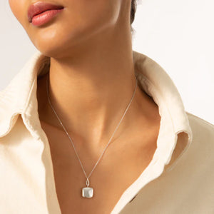 woman wear beige shirt with a silver necklace on a white background