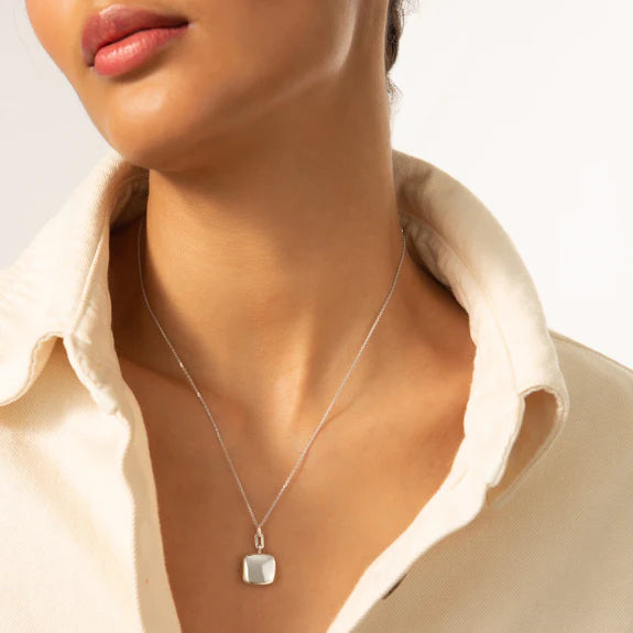 woman wear beige shirt with a silver necklace on a white background