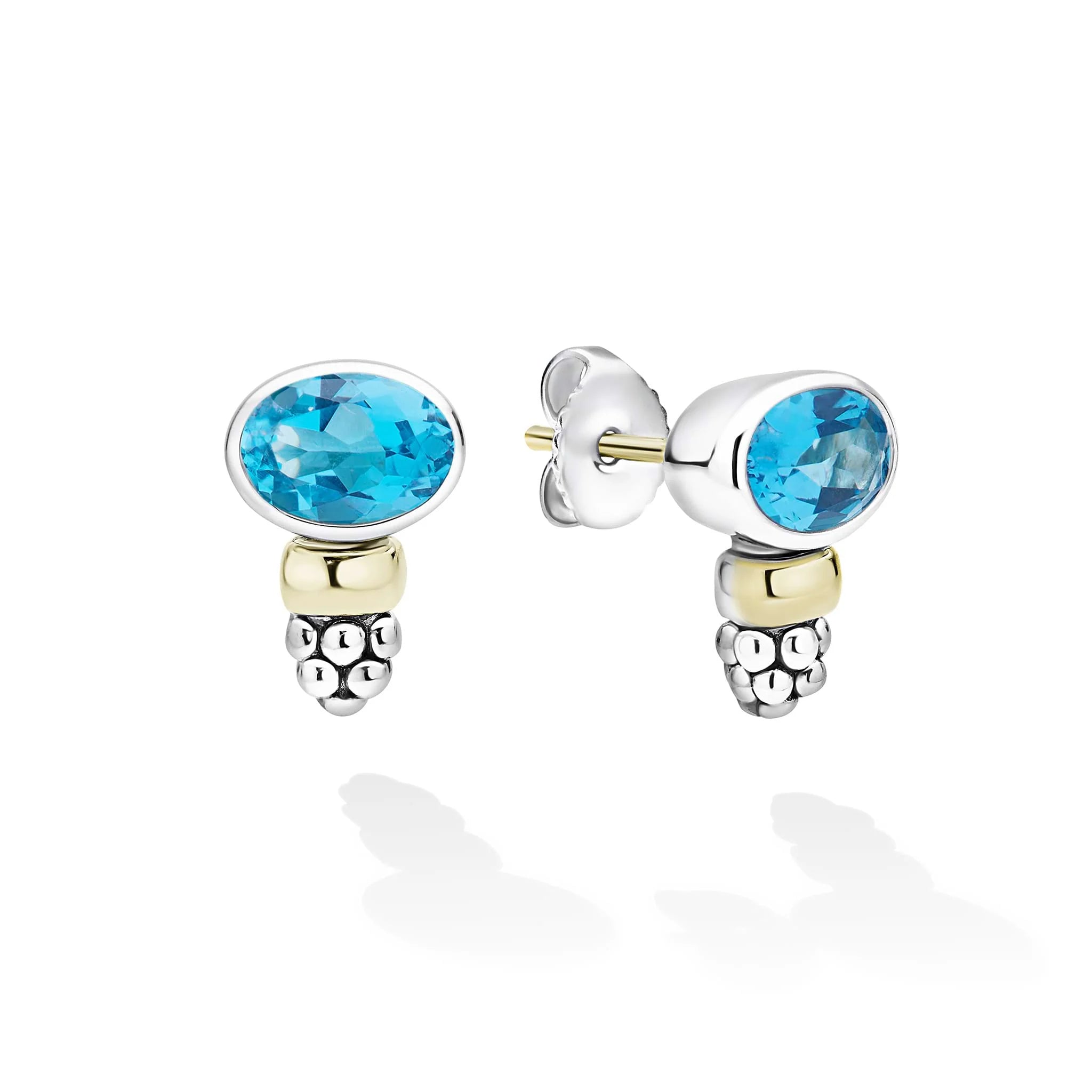 A pair of silver and yellow gold stud earrings with oval-cut light blue gemstones, shown on a clean white background with soft reflections.