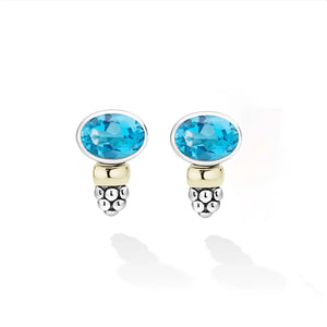 A pair of oval stud earrings featuring bright blue faceted gemstones in silver-toned bezel settings, with a polished gold bead and a textured silver bead cluster below, shown on a white background.