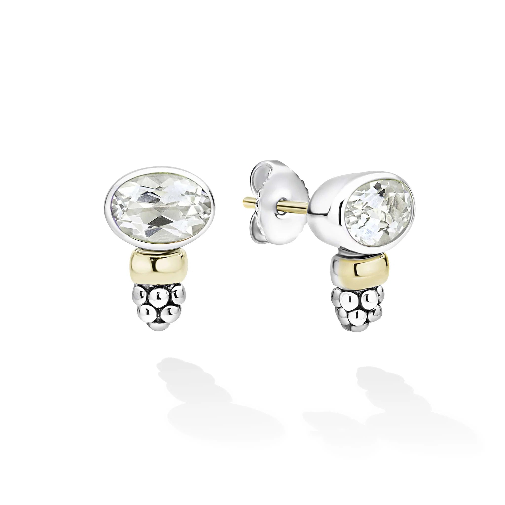 A pair of silver and yellow gold stud earrings with oval-cut white gemstones, shown on a clean white background with soft reflections.