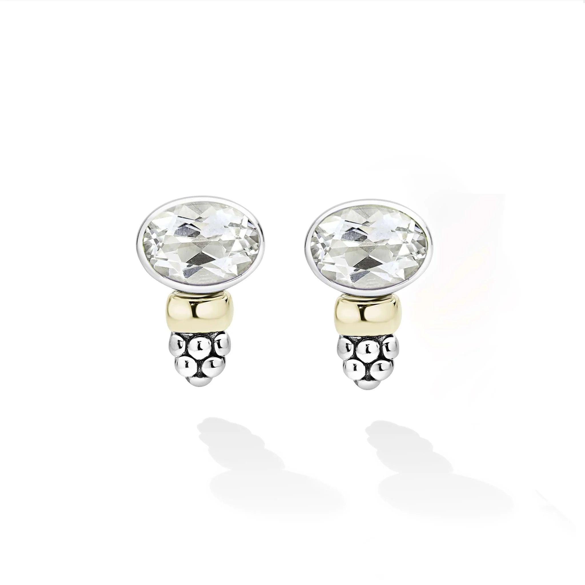 A pair of silver and yellow gold stud earrings with oval-cut white gemstones, shown on a clean white background with soft reflections.