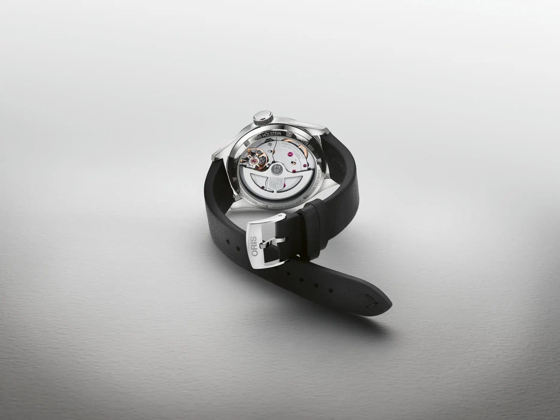Watch with black strap and silver case on a light gray background