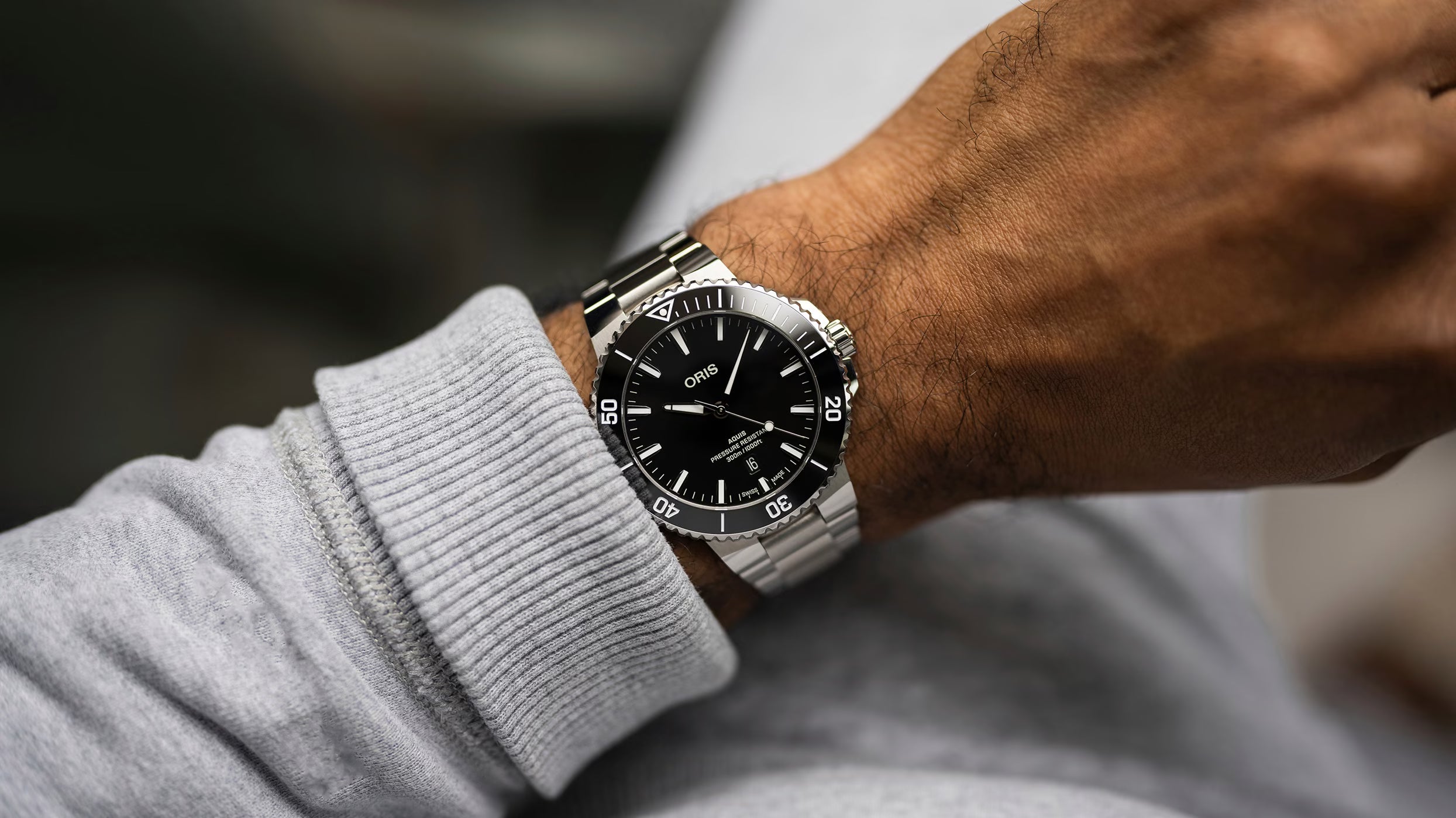 Close-up of a wrist wearing a silver watch with a black face.