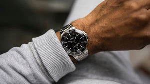 Close-up of a wrist wearing a silver watch with a black face.