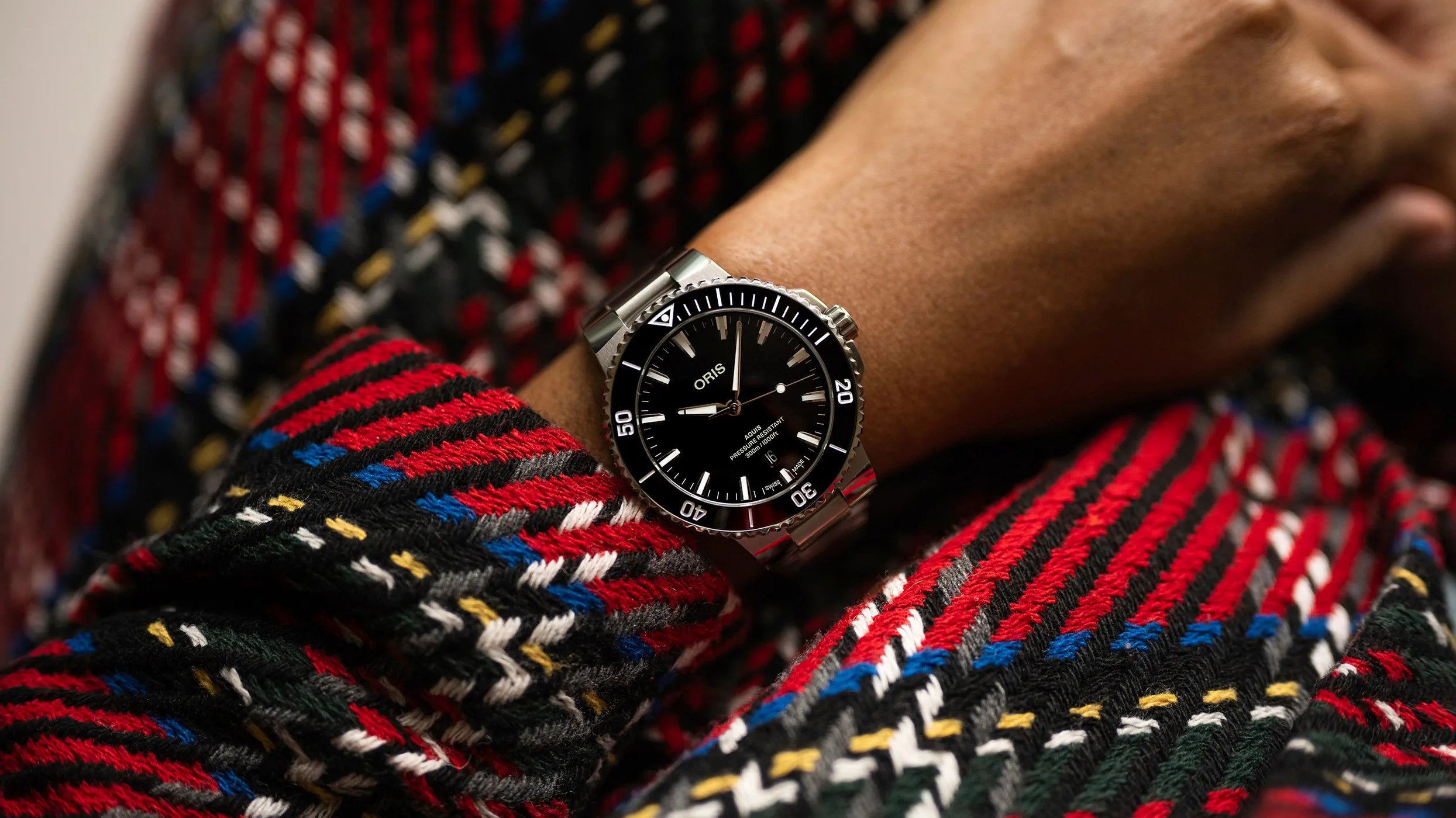 Close-up of a person wearing a watch with a colorful patterned fabric background
