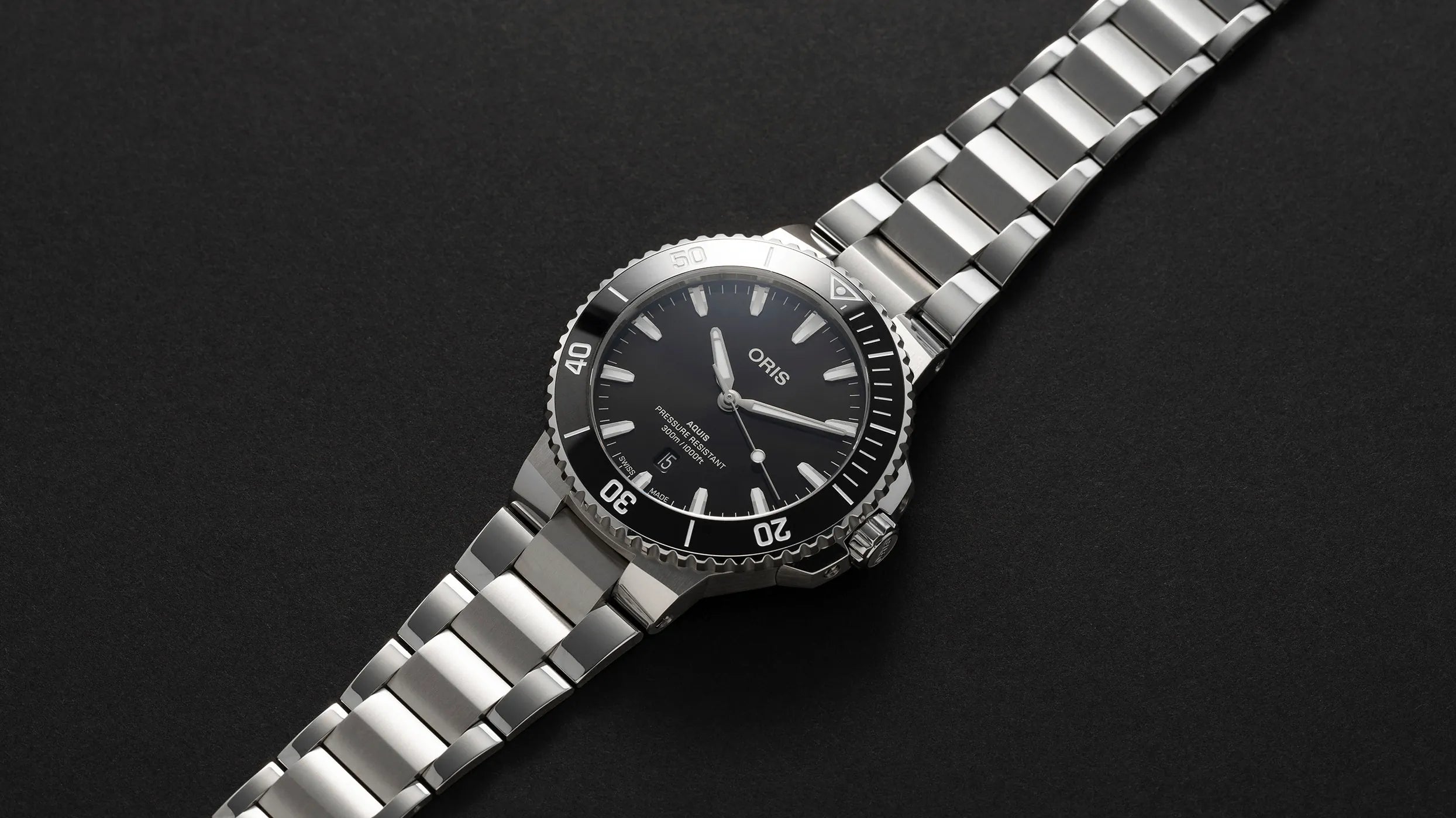 Silver Oris watch with black dial on a dark background
