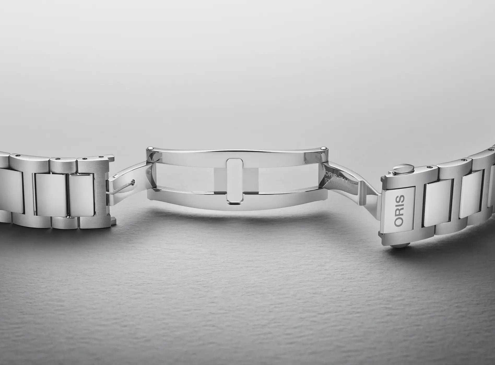Silver watch strap on a gray background