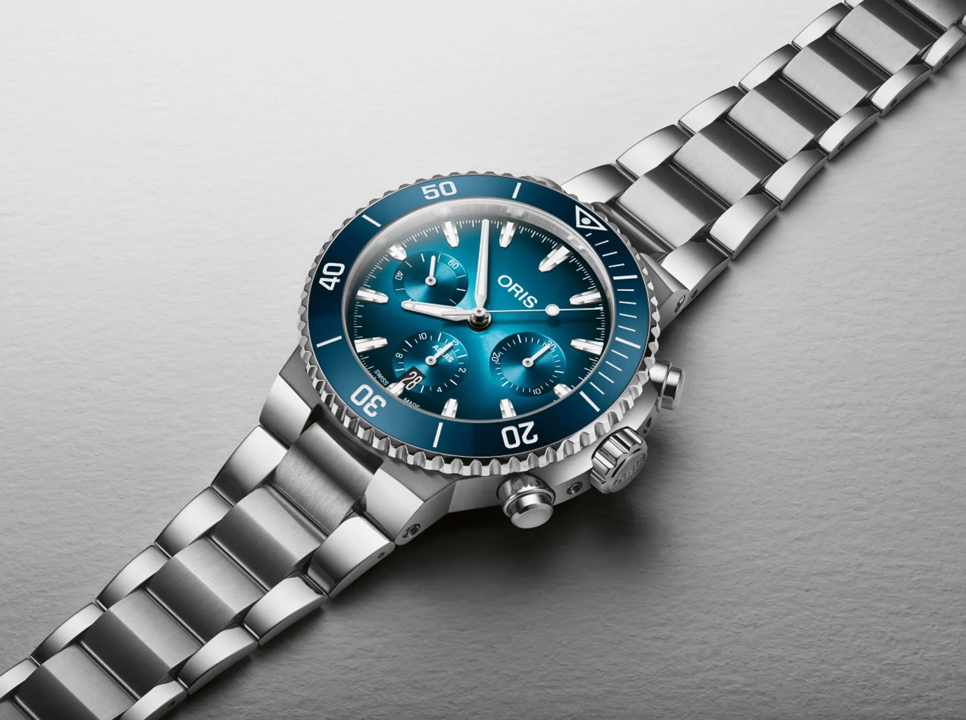 Silver Oris watch with blue face on a gray background