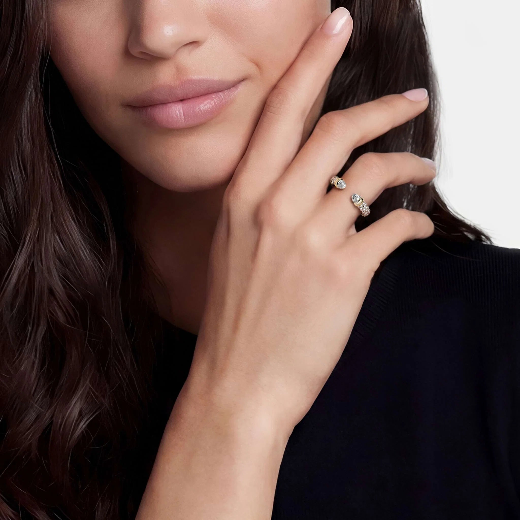 up close of a woman wearing black and an open two tone cuff ring on a light grey background