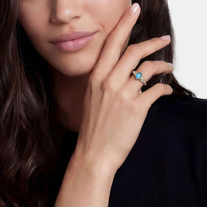 up close of a woman wearing black and a two tone ring with a blue oval center stone