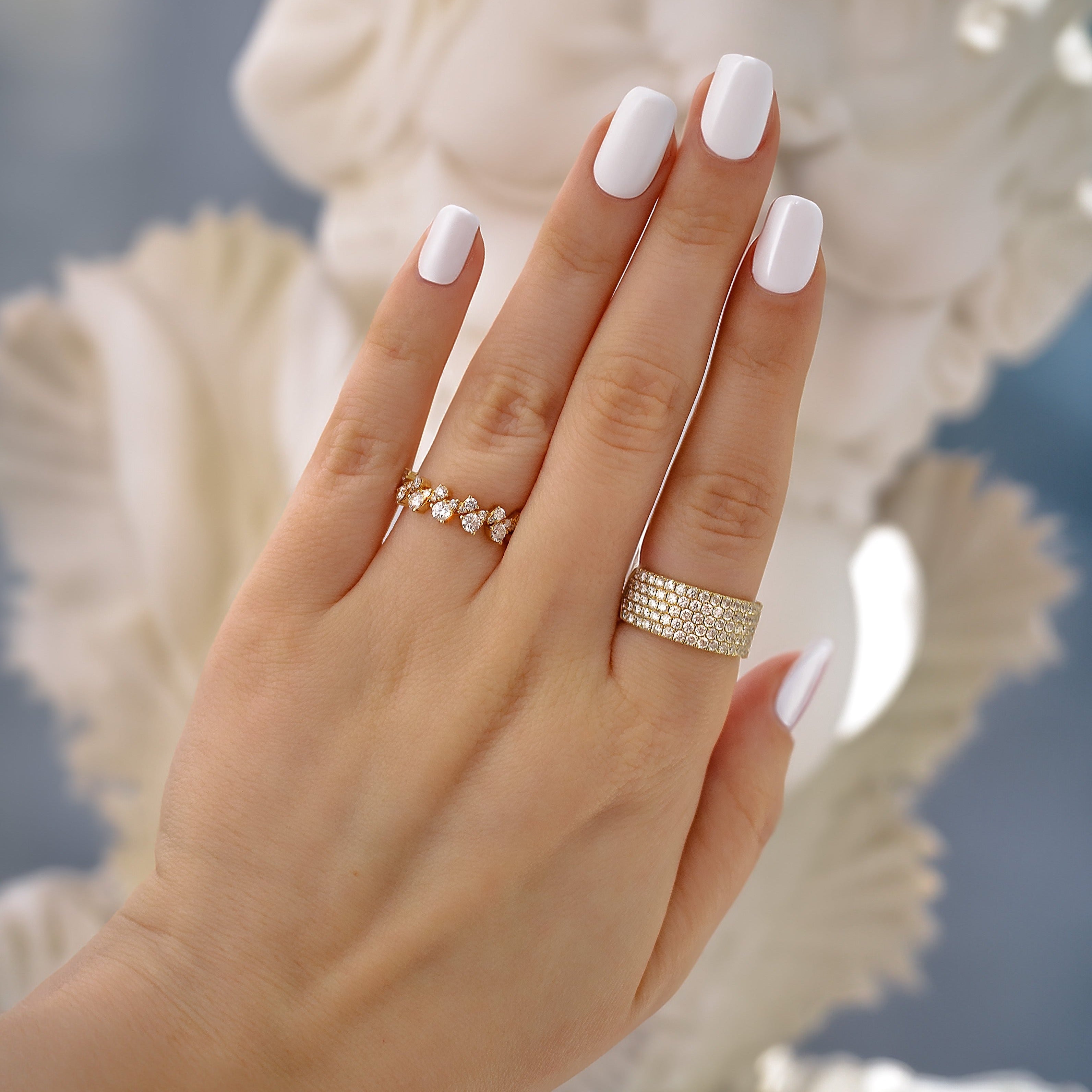 Close-up of hand wearing 14k yellow gold 0.71ctw diamond band with 24 diamonds on ring finger against soft background