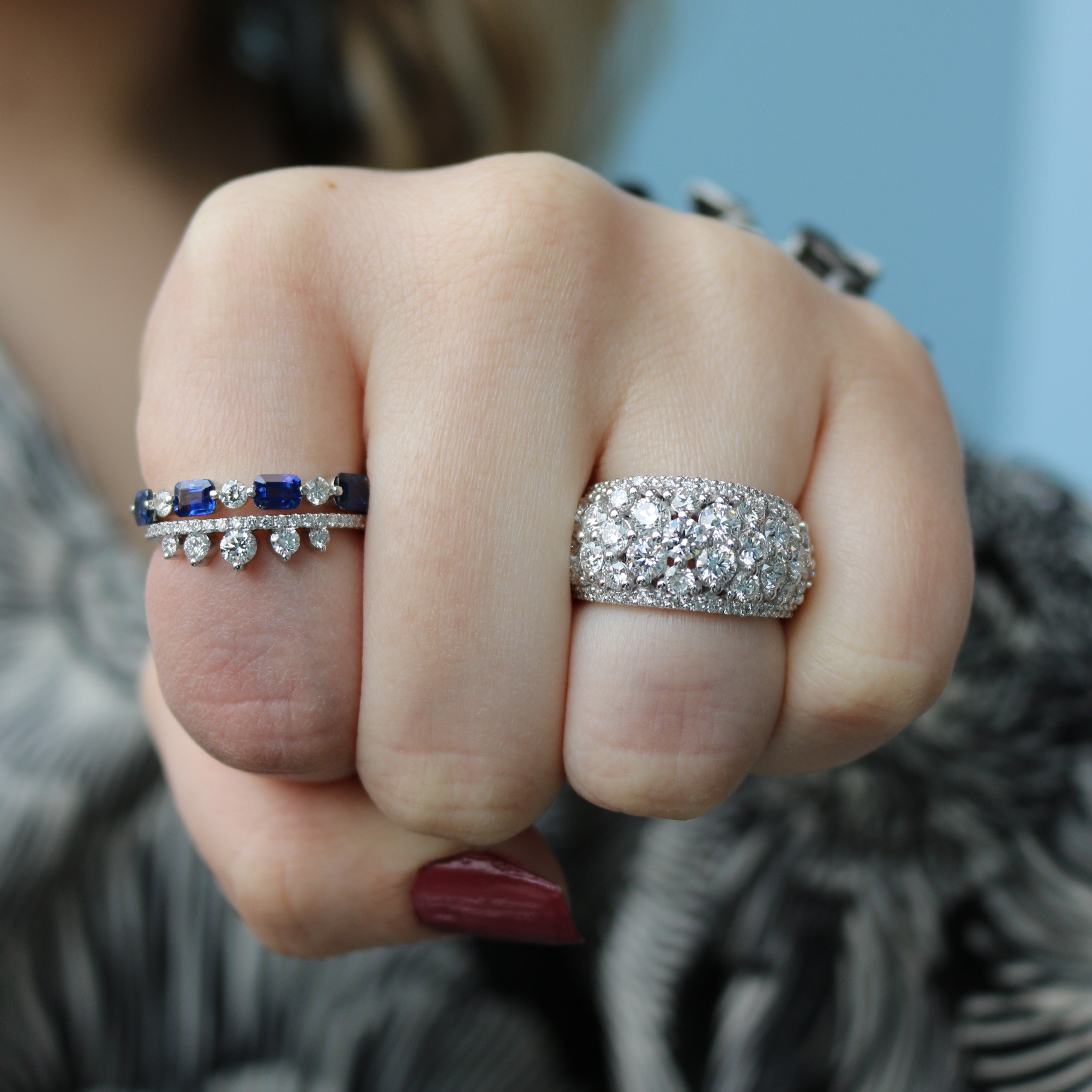 Front view of 0.43ctw diamond fashion ring showing pavé diamond dome on model's middle finger against blurred blue background