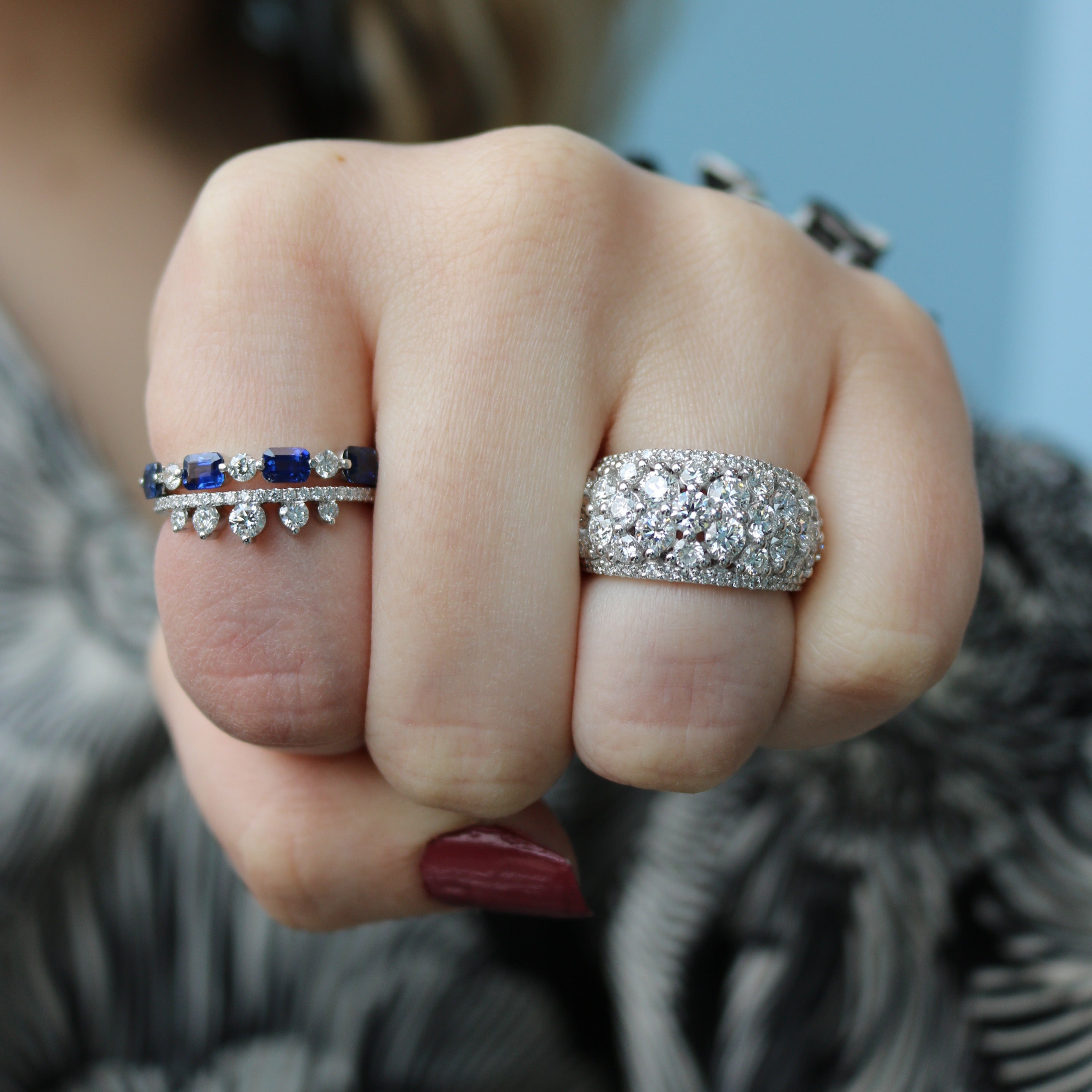 Hand wearing a blue sapphire band (0.21 ctw) with diamond accents beside a pavé diamond dome band