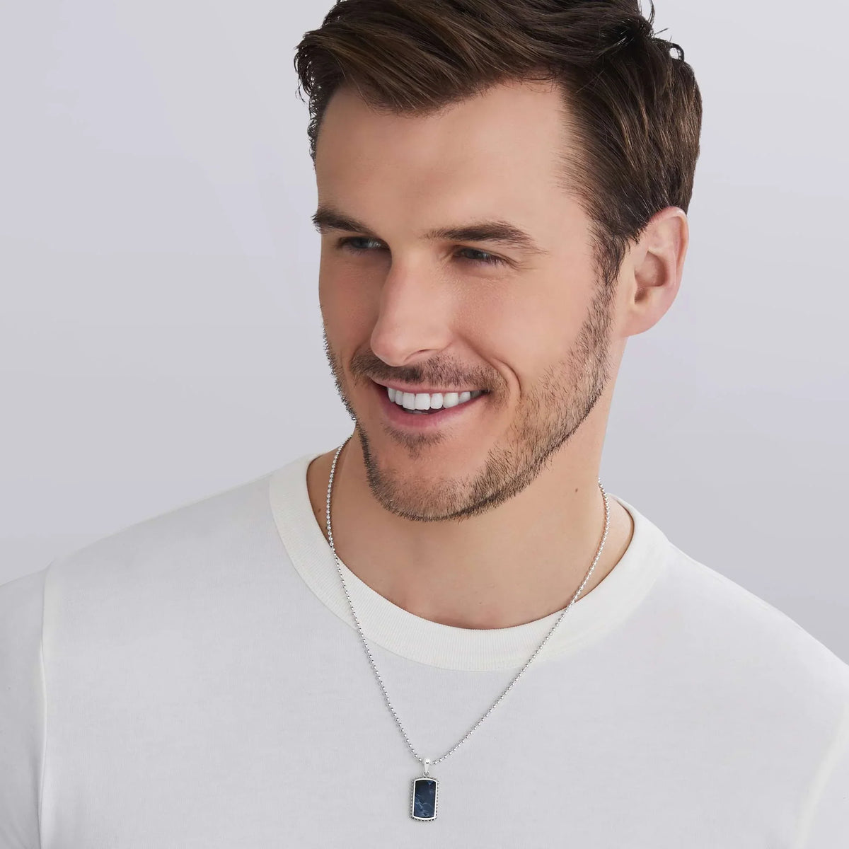 a man wearing a white tshirt and a Small Sterling Silver and Pietersite Tag Amulet on a white background