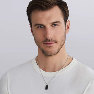 a man wearing a white tshirt and a  Small Sterling Silver and Black Agate Tag Amulet with beading around the edge on a white background
