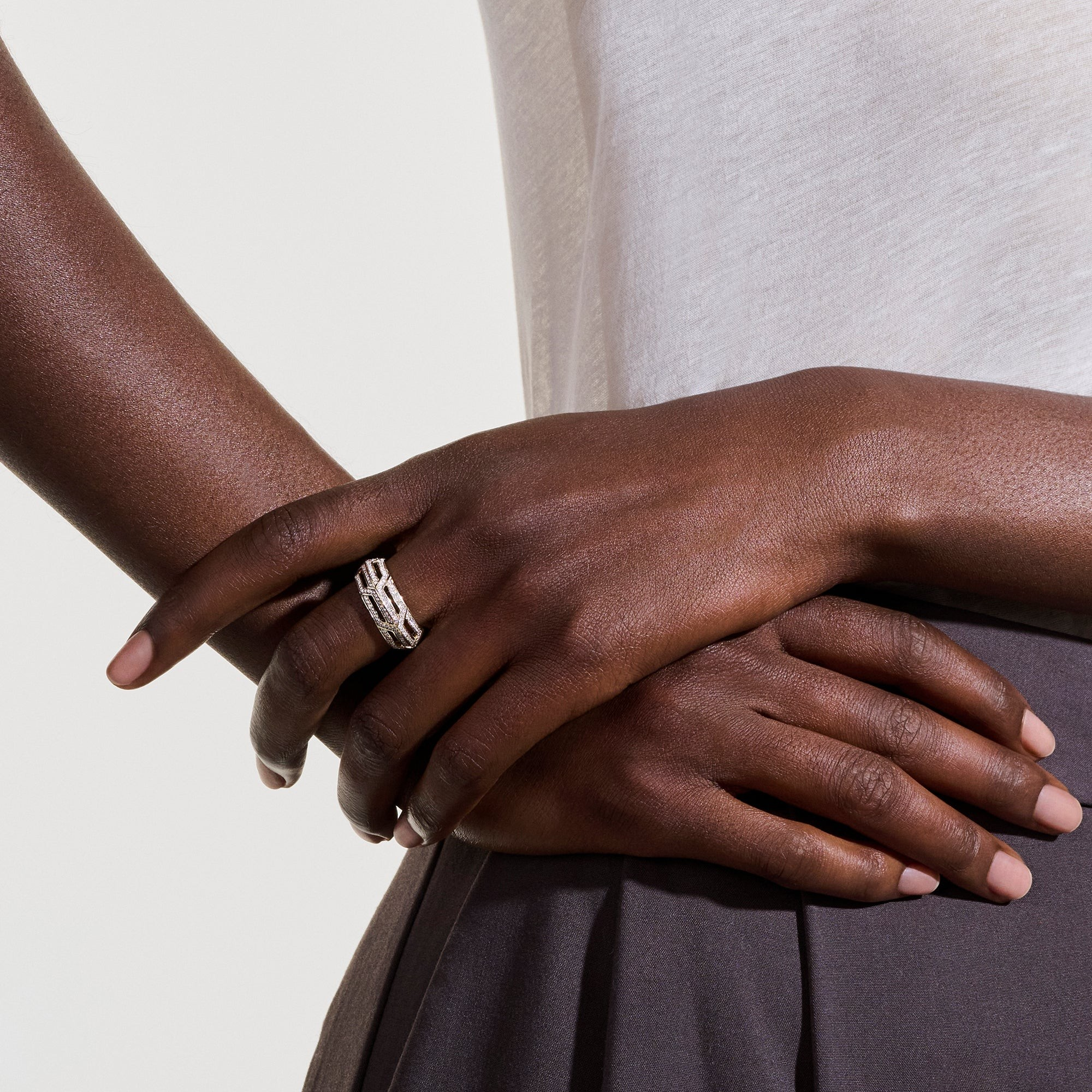 Close-up of hands wearing 14K yellow gold Diamond Icon ring showing chain-link design with pavé diamonds on neutral background
