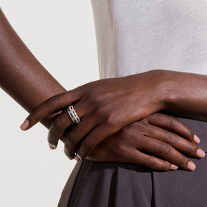 Close-up of hands wearing 14K yellow gold Diamond Icon ring showing chain-link design with pavé diamonds on neutral background
