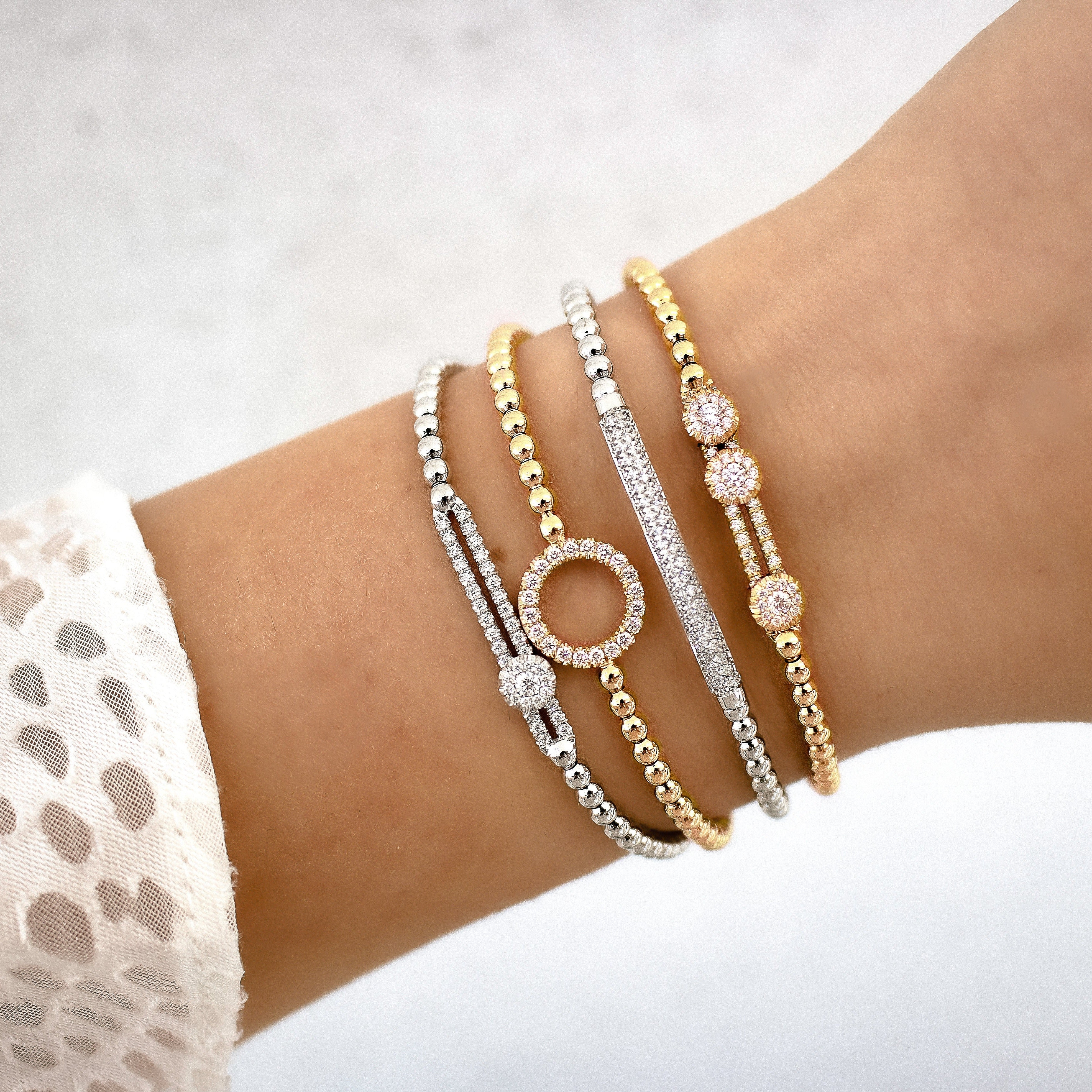 Close-up of wrist wearing four Tresore stretch bracelets in yellow and white gold, showing beaded bands and pavé diamond accents on white background