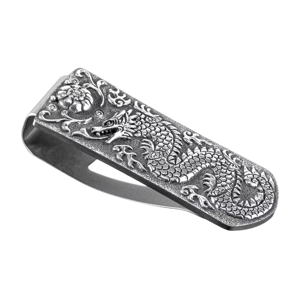 Angled view of William Henry Zurich Naga sterling silver money clip with hand-carved dragon and floral detail on white