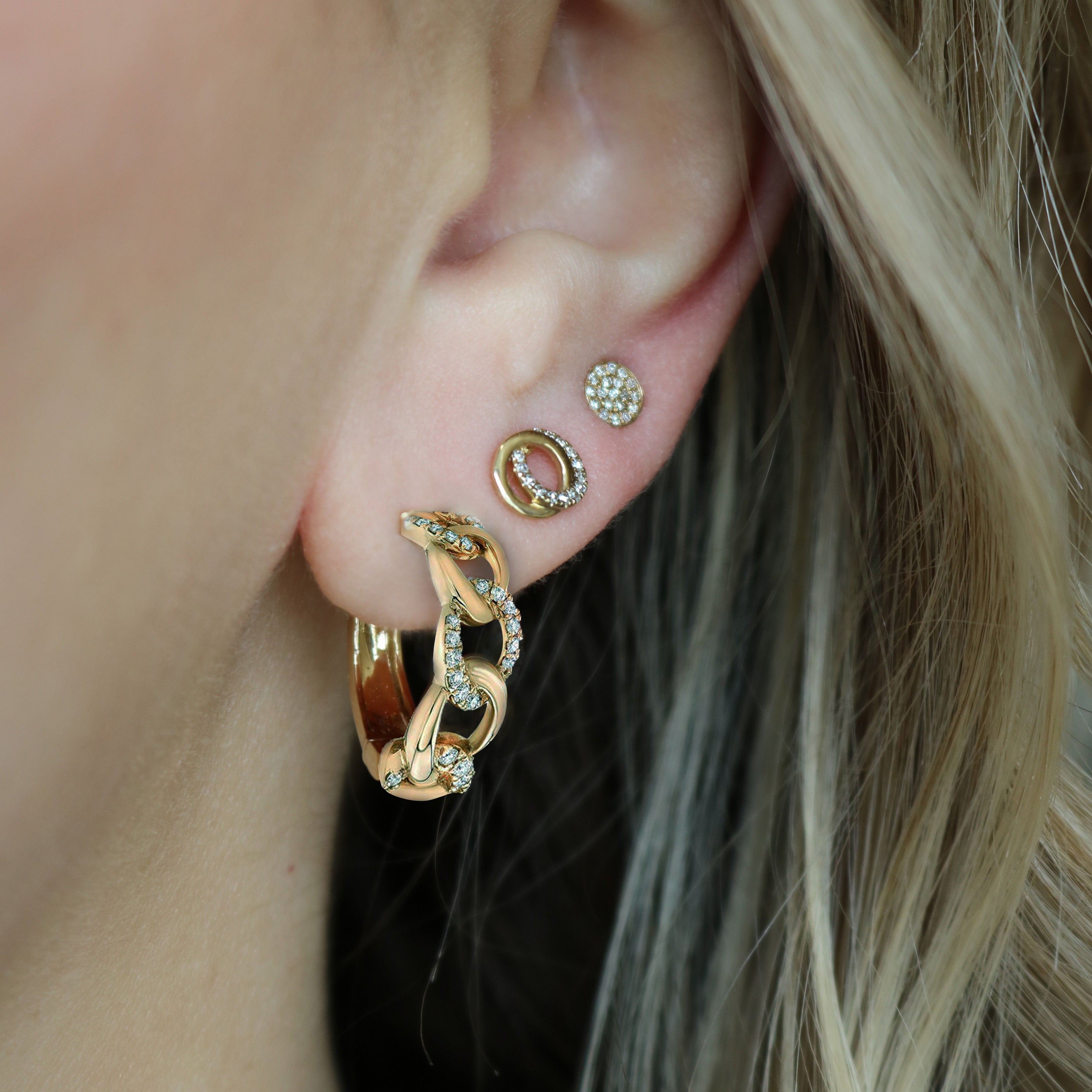 Close up of ear wearing 14K yellow gold Love Knot earring on earlobe showing interlocking circles with 0.09 ctw diamonds