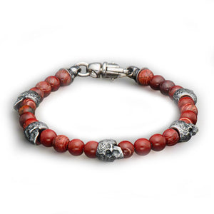 Red beaded bracelet with silver skull beads, decorative spacer beads, and a silver lobster clasp.