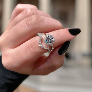 Close-up of .31ctw diamond curved wedding band in 14K white gold fitting around halo engagement ring on a hand