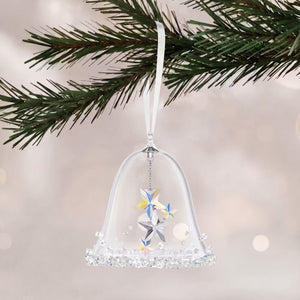 a glass and crystal bell hanging from a tree on a white shimmery background