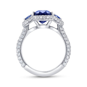 Side view of three-stone oval blue sapphire ring showcasing three oval sapphires and pavé diamond band on white background