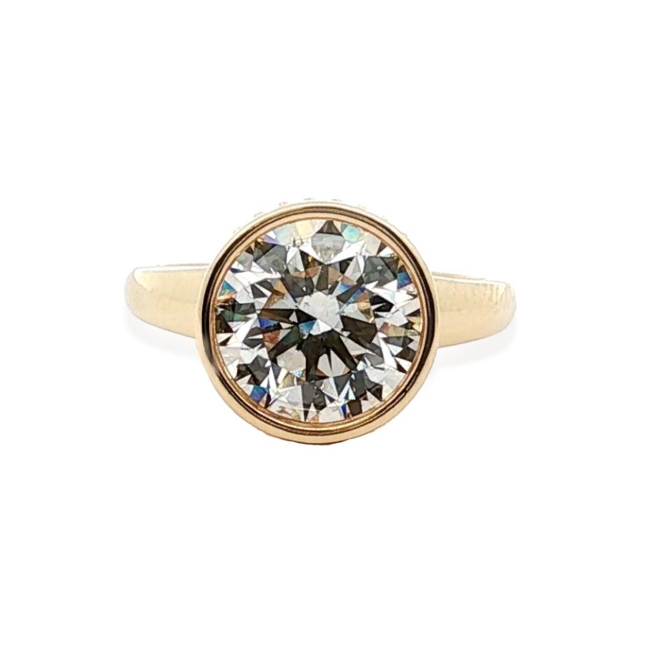 Front view of 18K yellow gold engagement ring showcasing 4.01 ct round bezel-set center diamond on white background